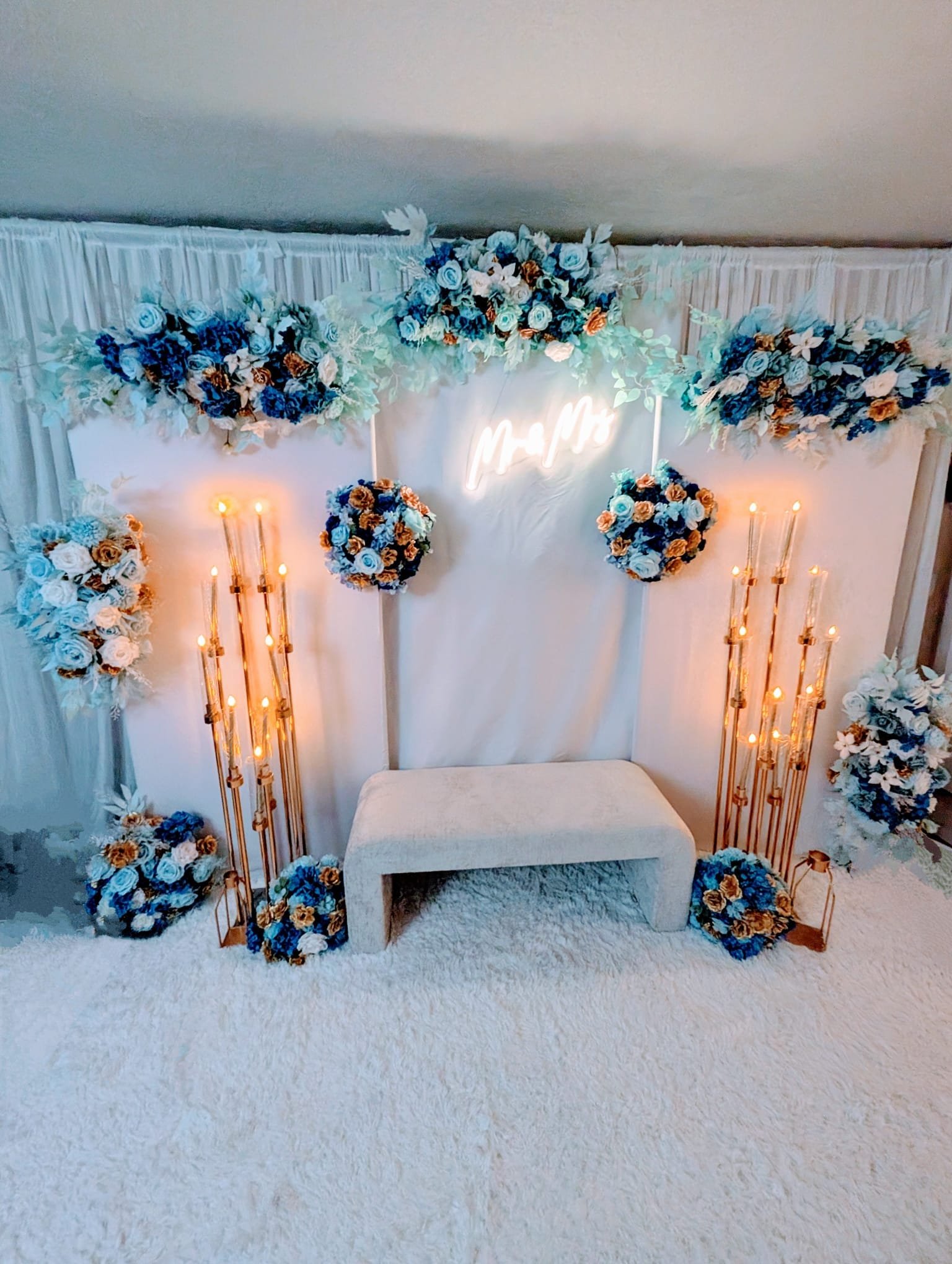 Blue and gold floral wedding backdrop with Mr & Mrs neon sign and candelabras