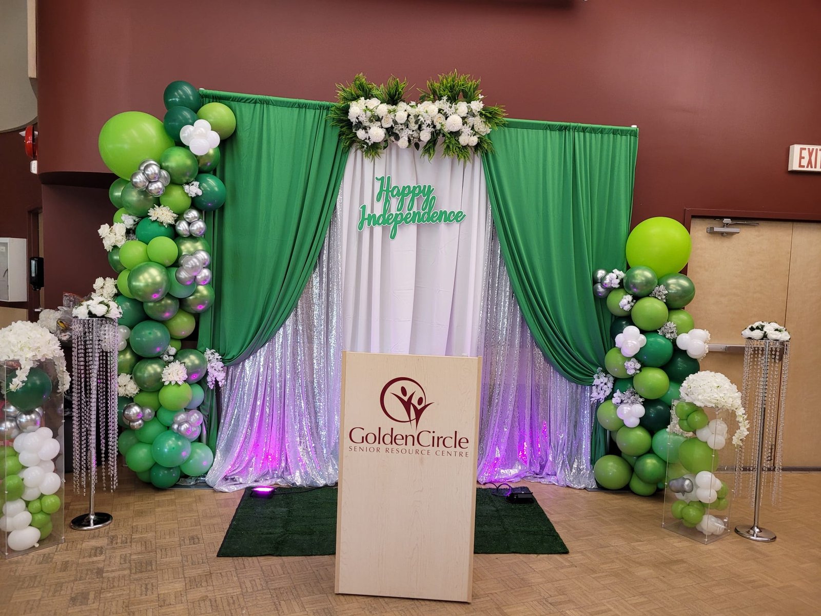 Green and white curtain backdrop with balloon garlands and florals
